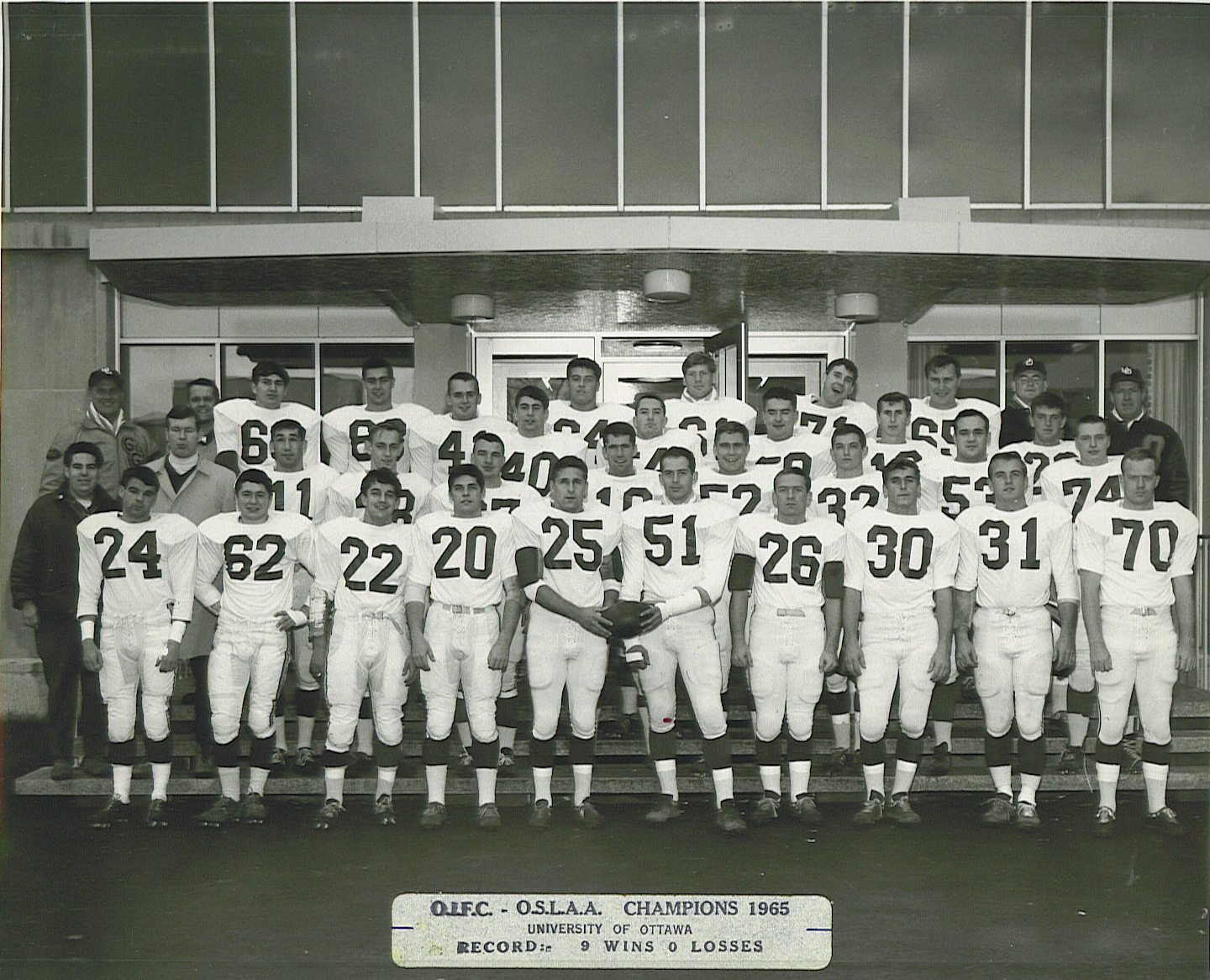 OIFC-OSLAA Champions 1965, University of Ottawa football team photo. Black and white photo taken on the steps of a building on campus.