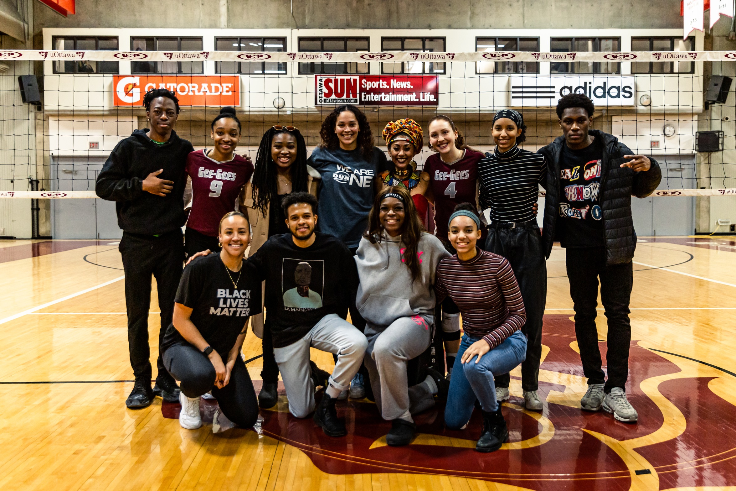 A group poses together in the gymnasium in front of a volleyball net