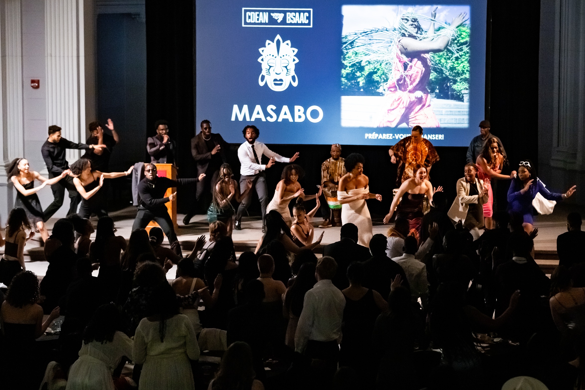 A large group of people dancing in a circle, dressed in formal attire