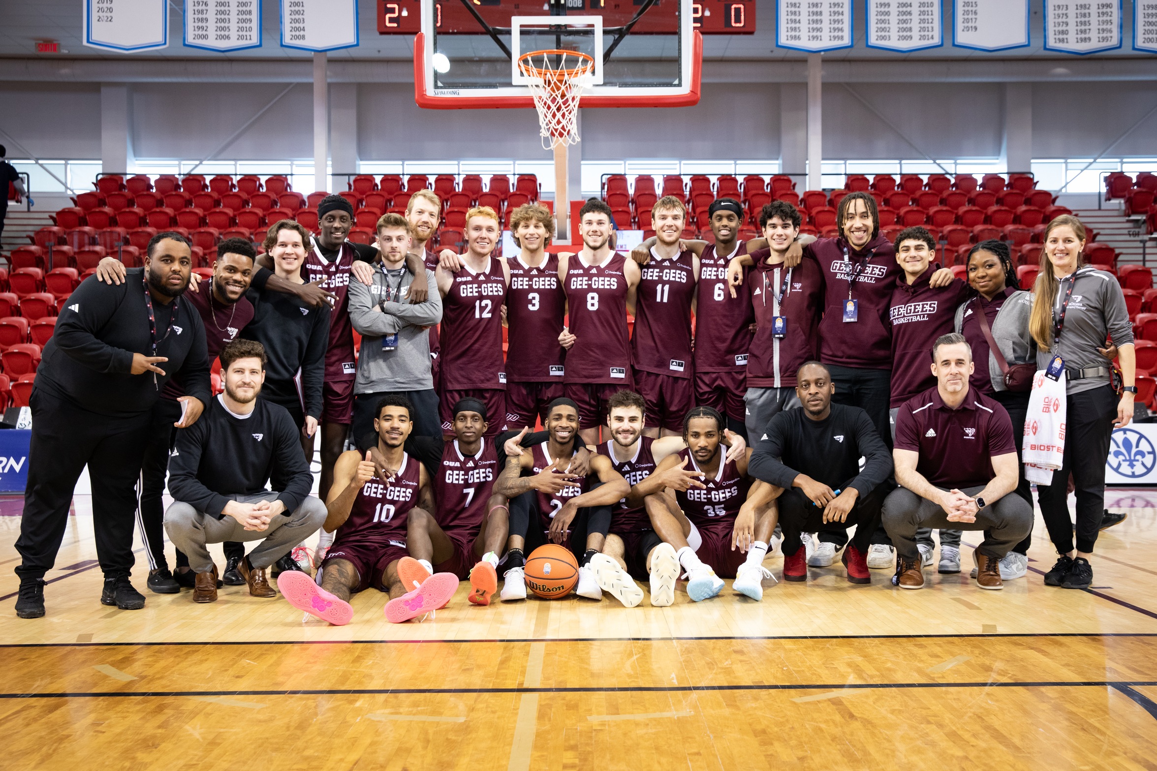 Team photo of the men's basketball team players and staff with their bronze medals at the University of Laval gym.