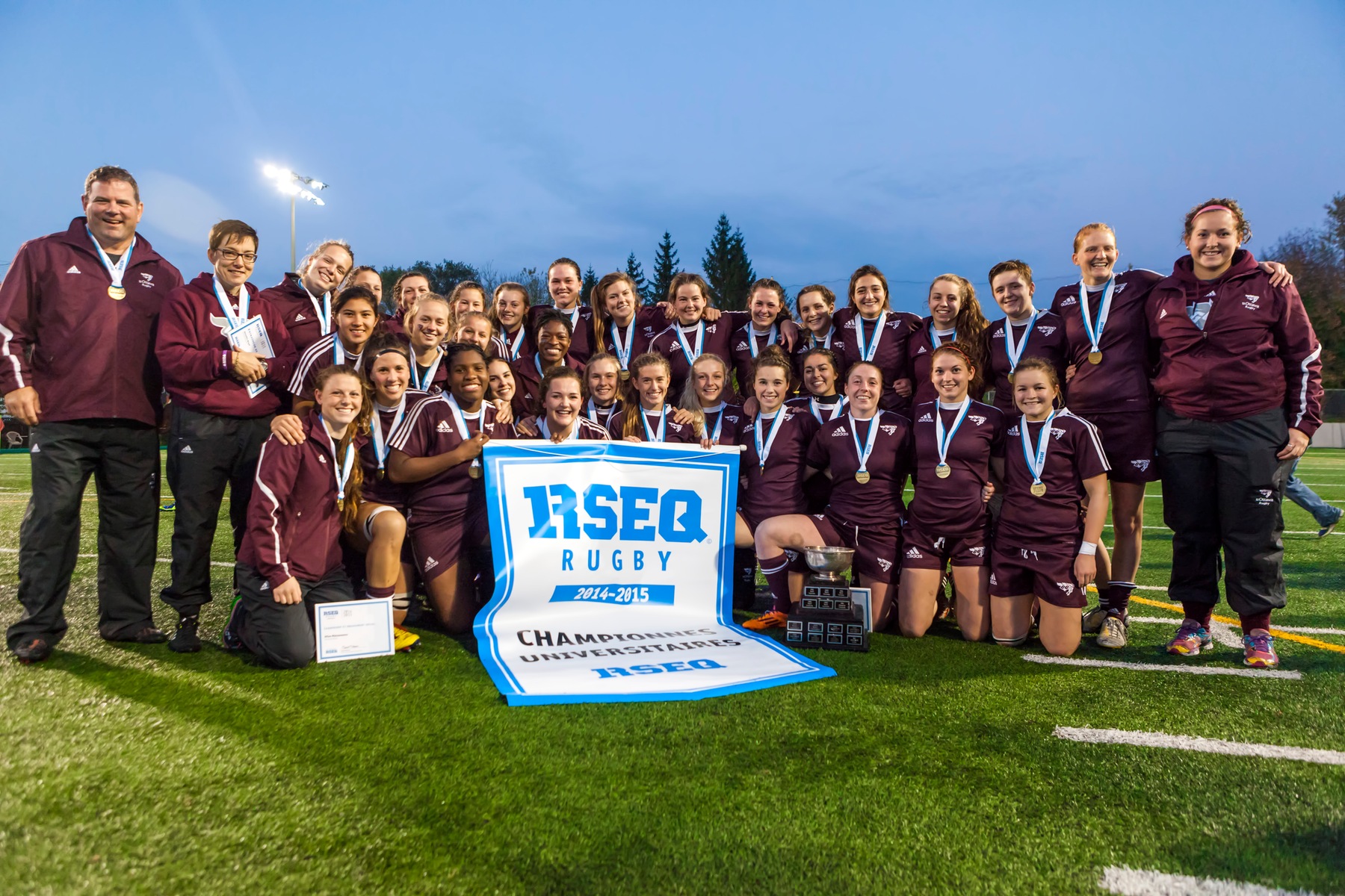 Team holds 2014 RSEQ championship banner at Matt Anthony Field.