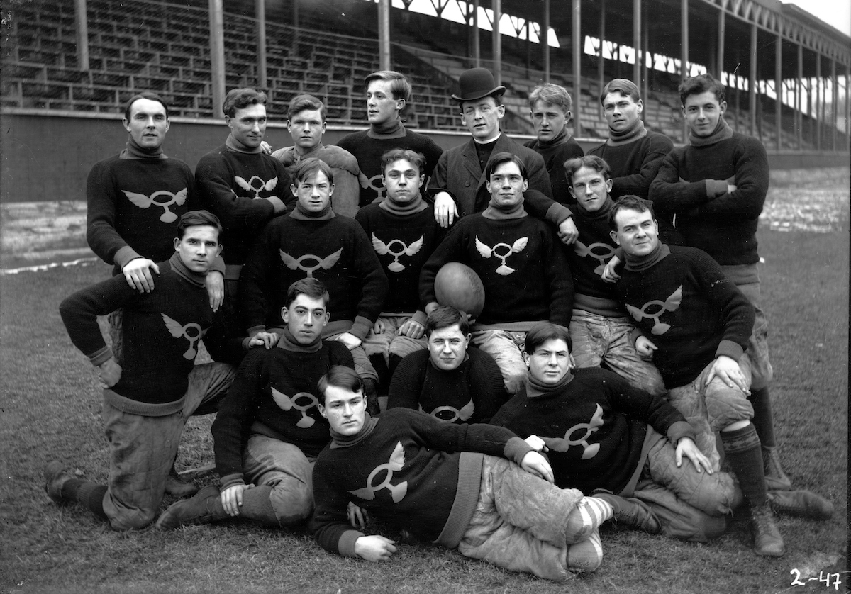 Photographie des membres d&rsquo;une &eacute;quipe de football en uniforme encompagnie de leur entra&icirc;neur le P&egrave;re William Stanton o.m.i. On peut voir l&rsquo;ancienneestrade derri&egrave;re eux. - [1901-1915]. - 1 n&eacute;gatif : noir et blanc; 12,5 x 10 cm et 1photographie : noir et blanc; 18 x 13 cm. - Cr&eacute;dit : Archives de l&rsquo;Universit&eacute; Saint-Paul.