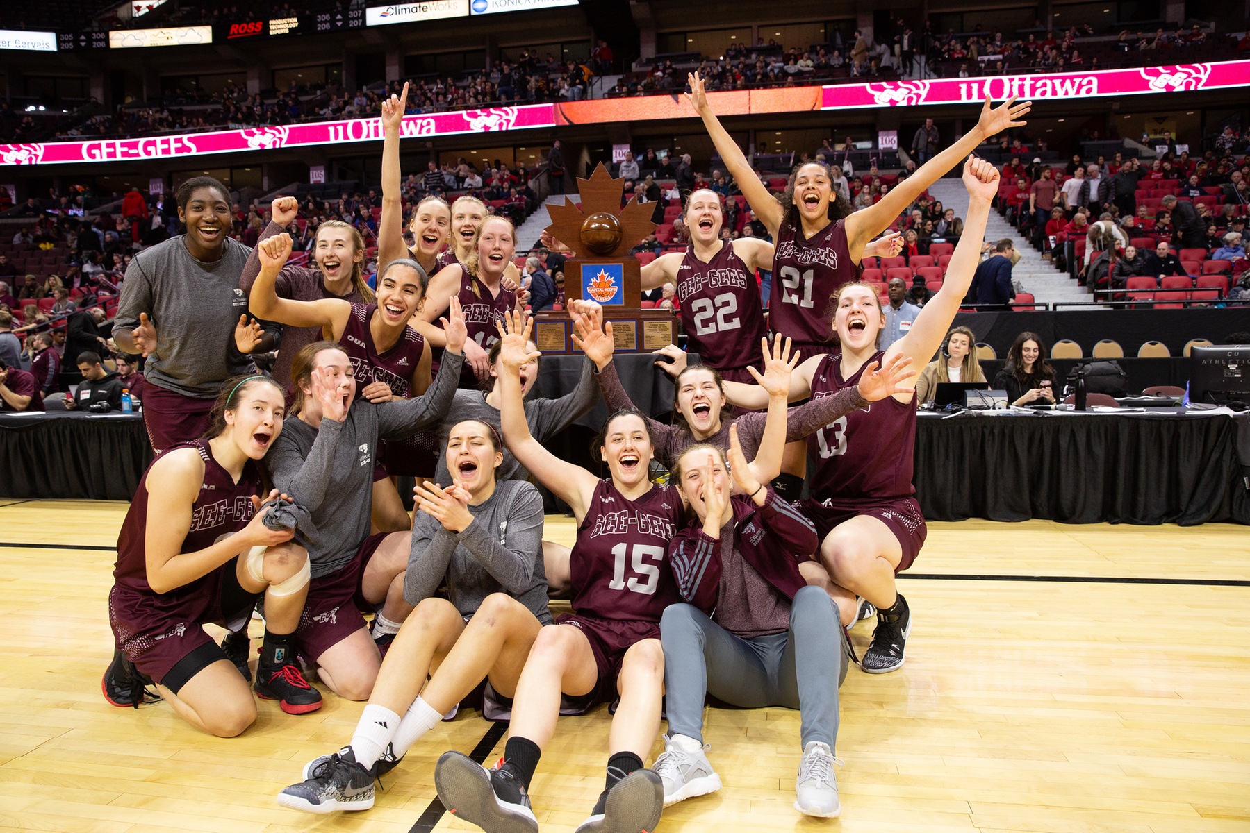 Team cheers around the Capital Hoops Classic trophy at Canadian Tire Centre.